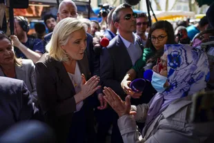 Far-right candidate Marine Le Pen speaks to a woman during a campaign rally at a market in Pertuis, France, Friday, April 15, 2022. (AP Photo/Daniel Cole)