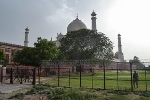 Security personnel stand guard behind a perimeter fence at the Taj Mahal