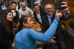 Australian opposition leader Anthony Albanese takes a selfie with supporters at a cafe in Sydney, Thursday, April 21, 2022. 