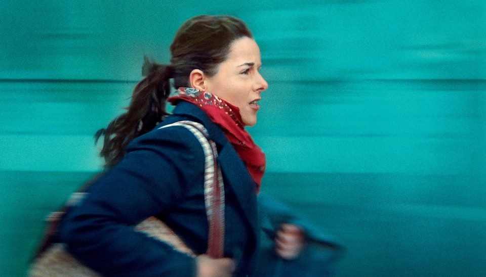Light-skinned woman, long black hair, blue jacket, red scarf, carrying a bag - Metropolis