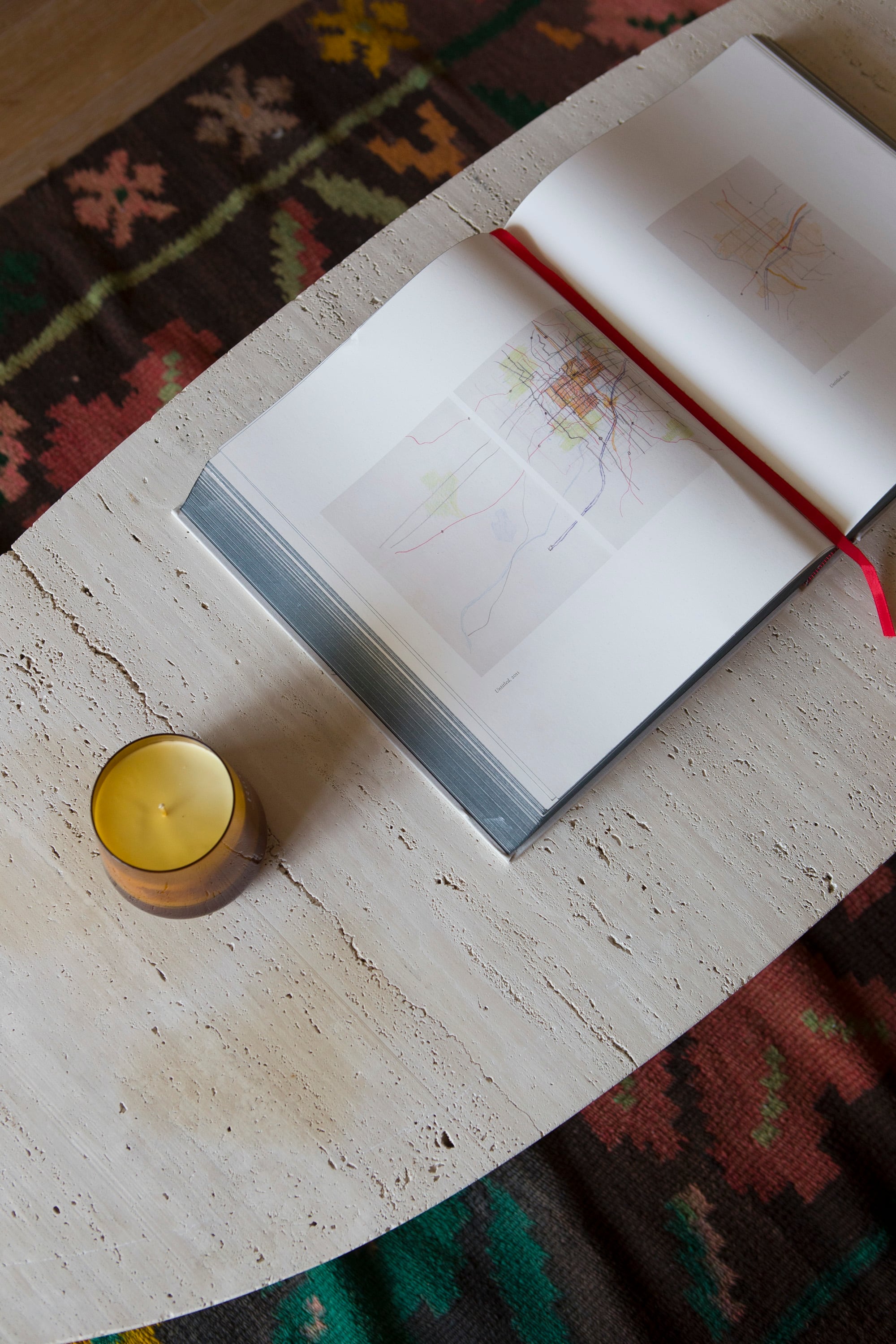 In a double layer of textures, woven carpet and stone oval table. 